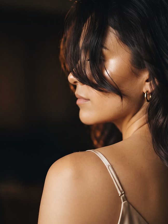 Mujer de perfil con la piel iluminada por luz cálida